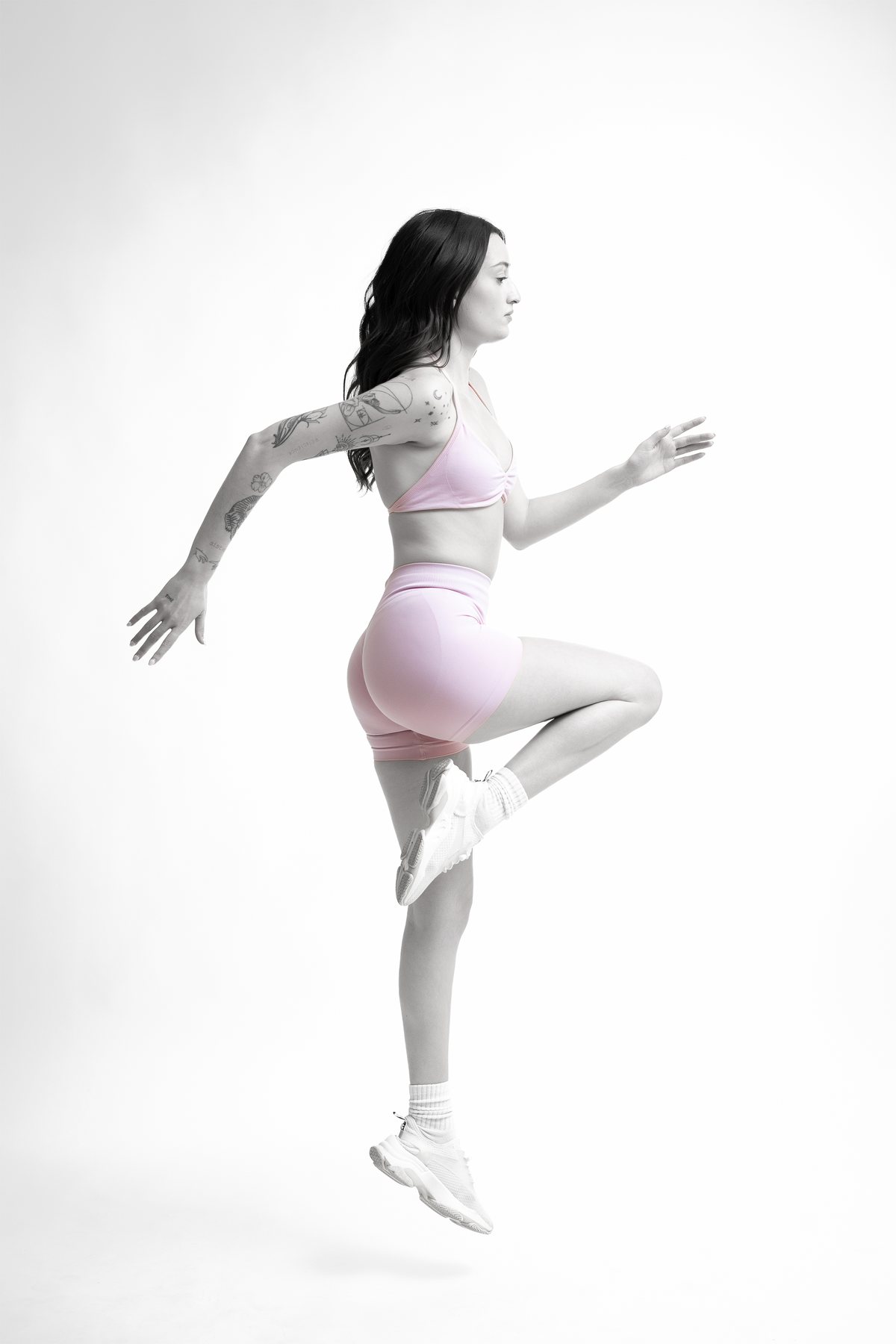 Activewear photography — model mid-stride in a pink set, monochrome with colour on the garment, Melbourne studio