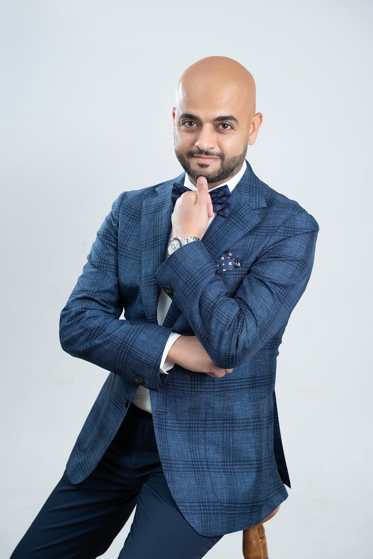 Seated personal branding portrait — blue check blazer, hand at chin, relaxed smile — LinkedIn and business portraits, Fraser Rise studio, Melbourne