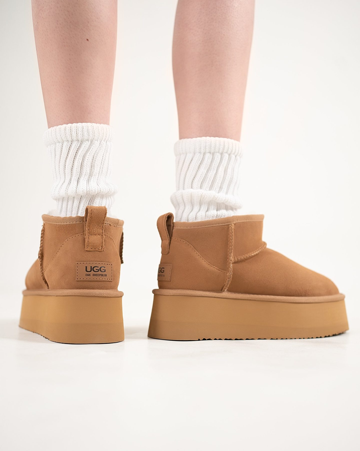 Footwear product detail — rear view of chestnut platform sheepskin boots with leather heel label and ribbed white socks