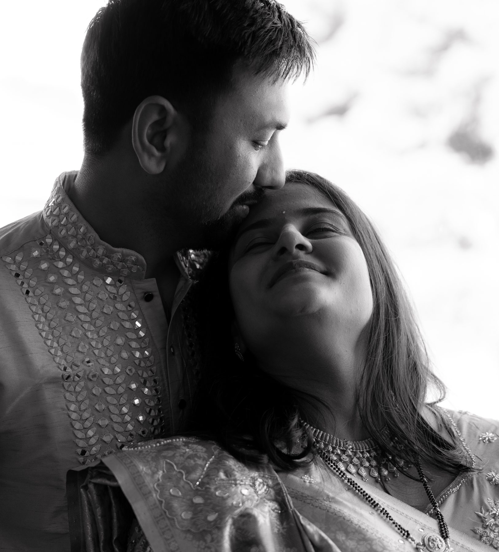 Black and white — husband kisses his wife on the forehead, mirror-work kurta — baby shower portrait Melbourne
