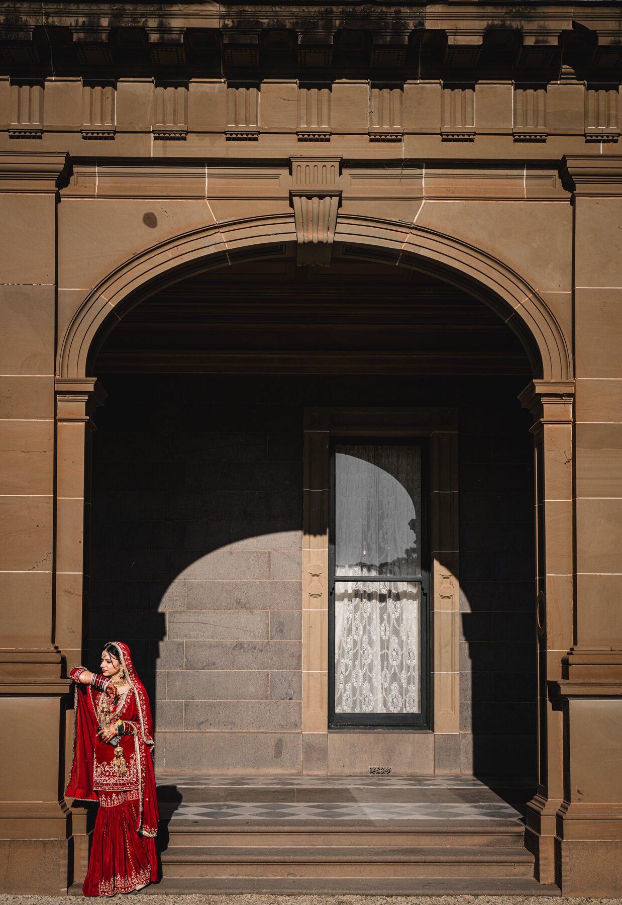 Gradient — bride and groom in colonnaded corridor, formal Sikh wedding