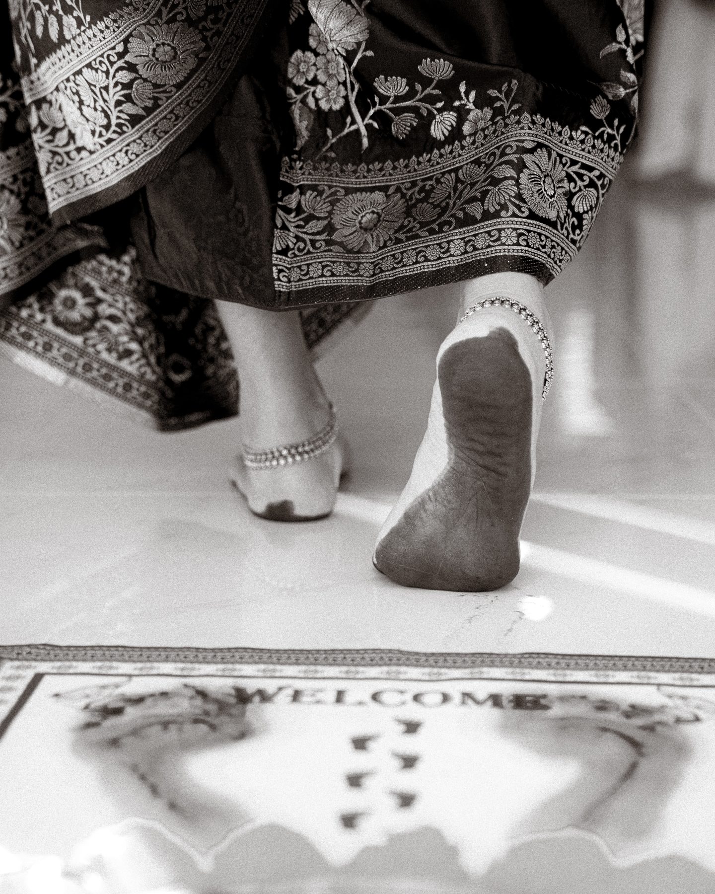Black and white — feet stepping onto a welcome mat of a new home, Griha Pravesh — Melbourne