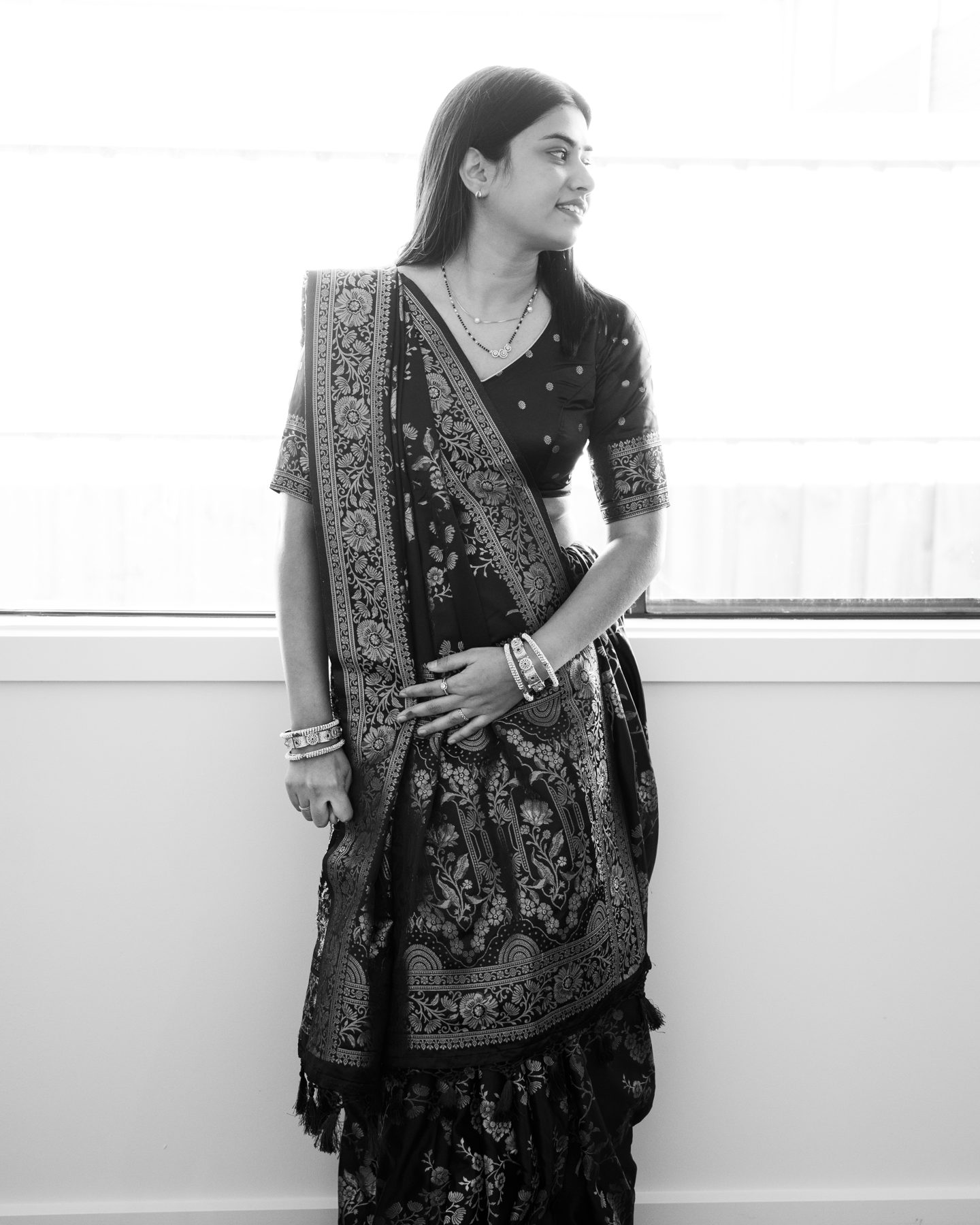 Black and white — woman in an embroidered sari smiling by a window, house warming — Melbourne