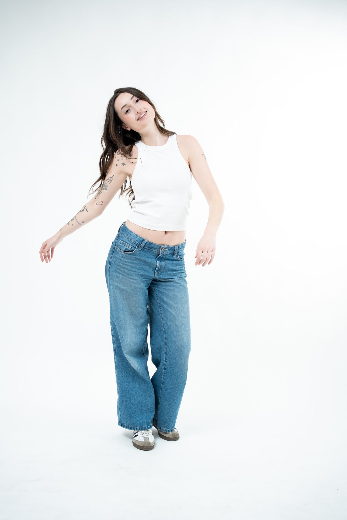 Model mid-movement in a white tank and blue wide-leg jeans, arm swinging and hair in motion — fashion lookbook photography Melbourne