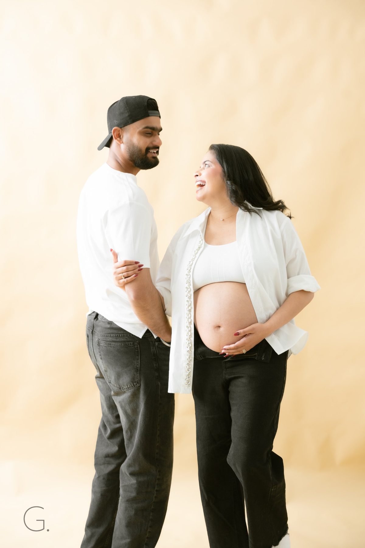 Expecting couple laughing together in white shirts and denim — candid maternity photography Melbourne