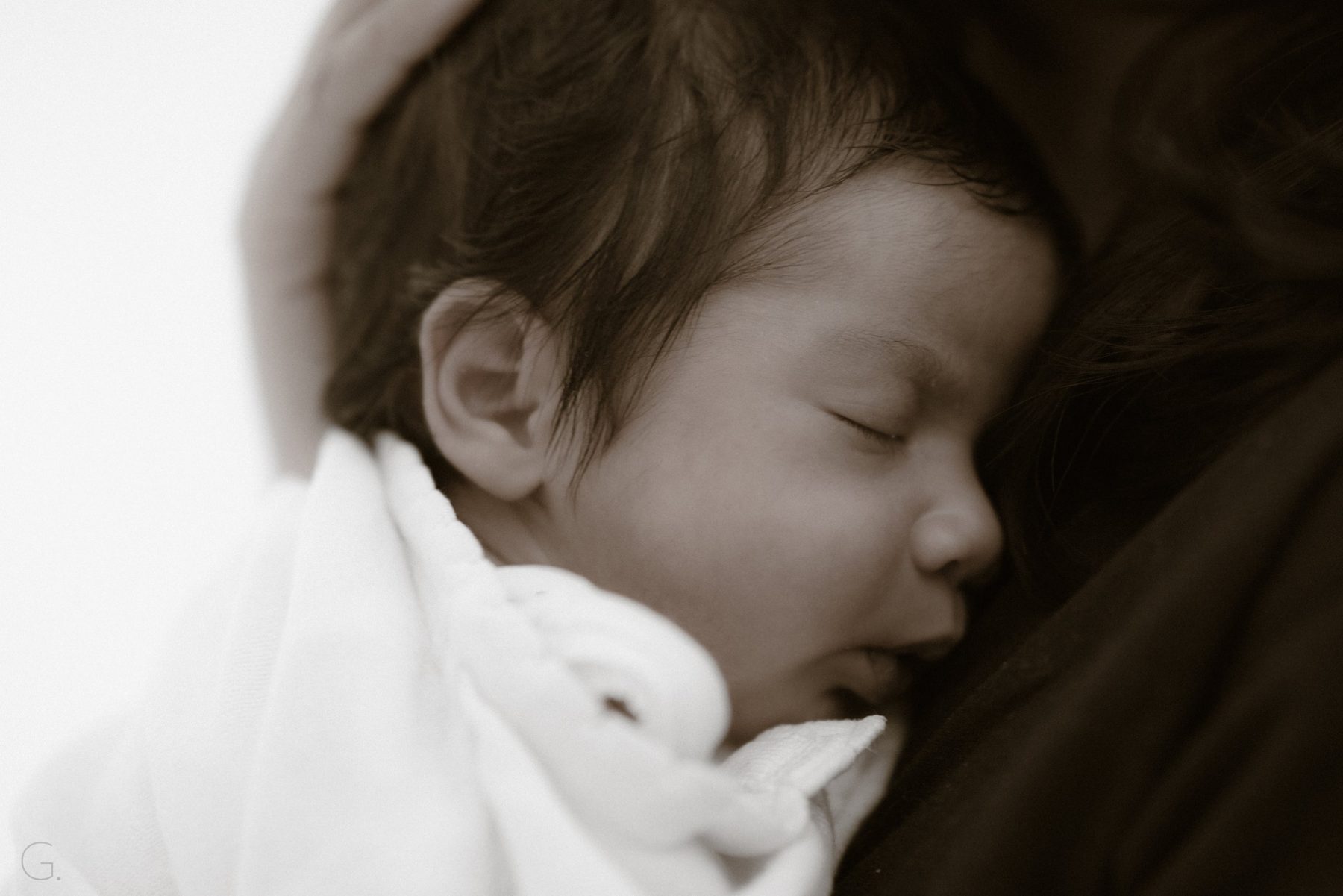 Sleeping newborn on a parent's chest in soft sepia tones — newborn photography Melbourne