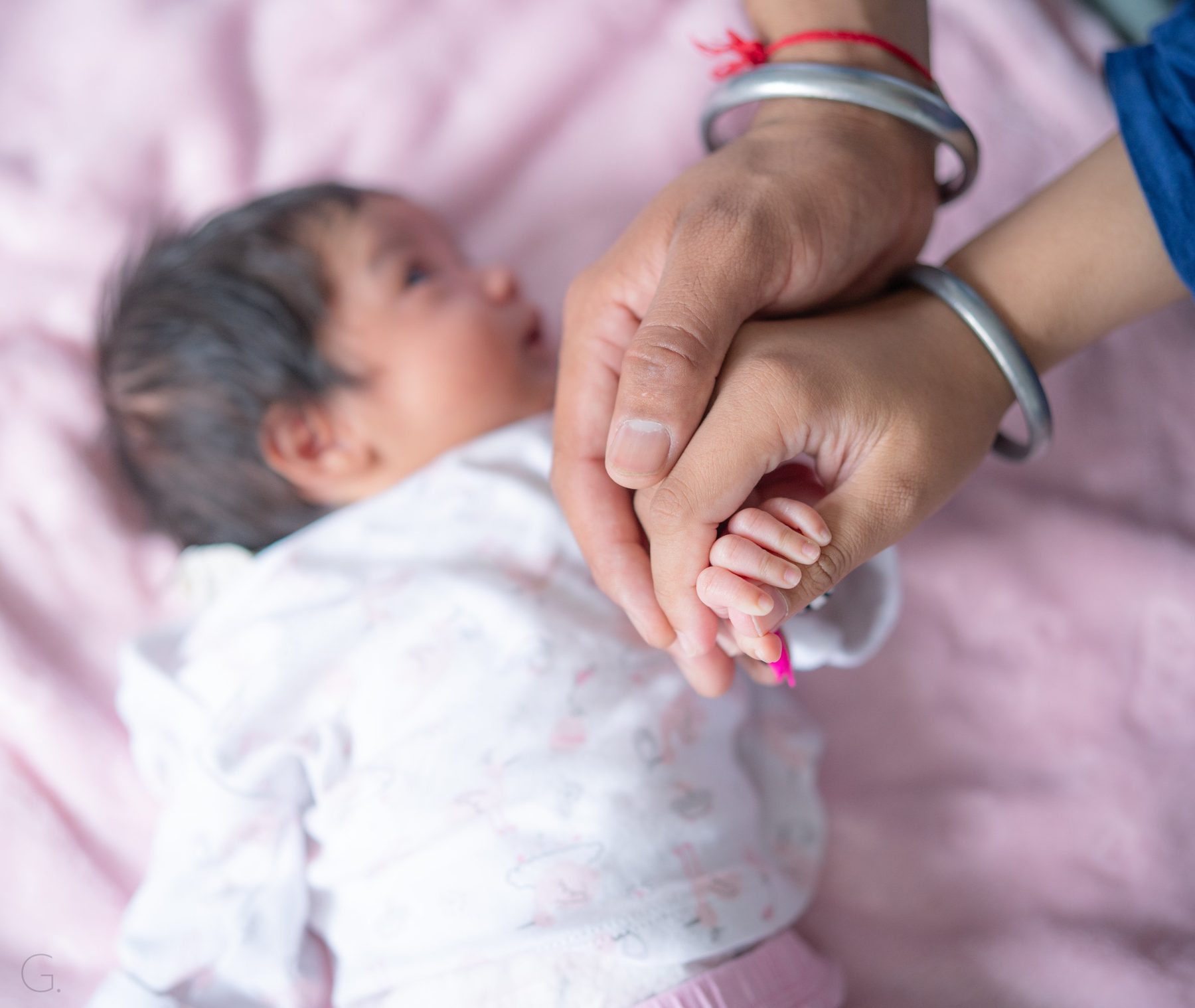 Parents' hands with kara bangles holding their newborn's tiny fingers — Sikh family newborn photography Melbourne