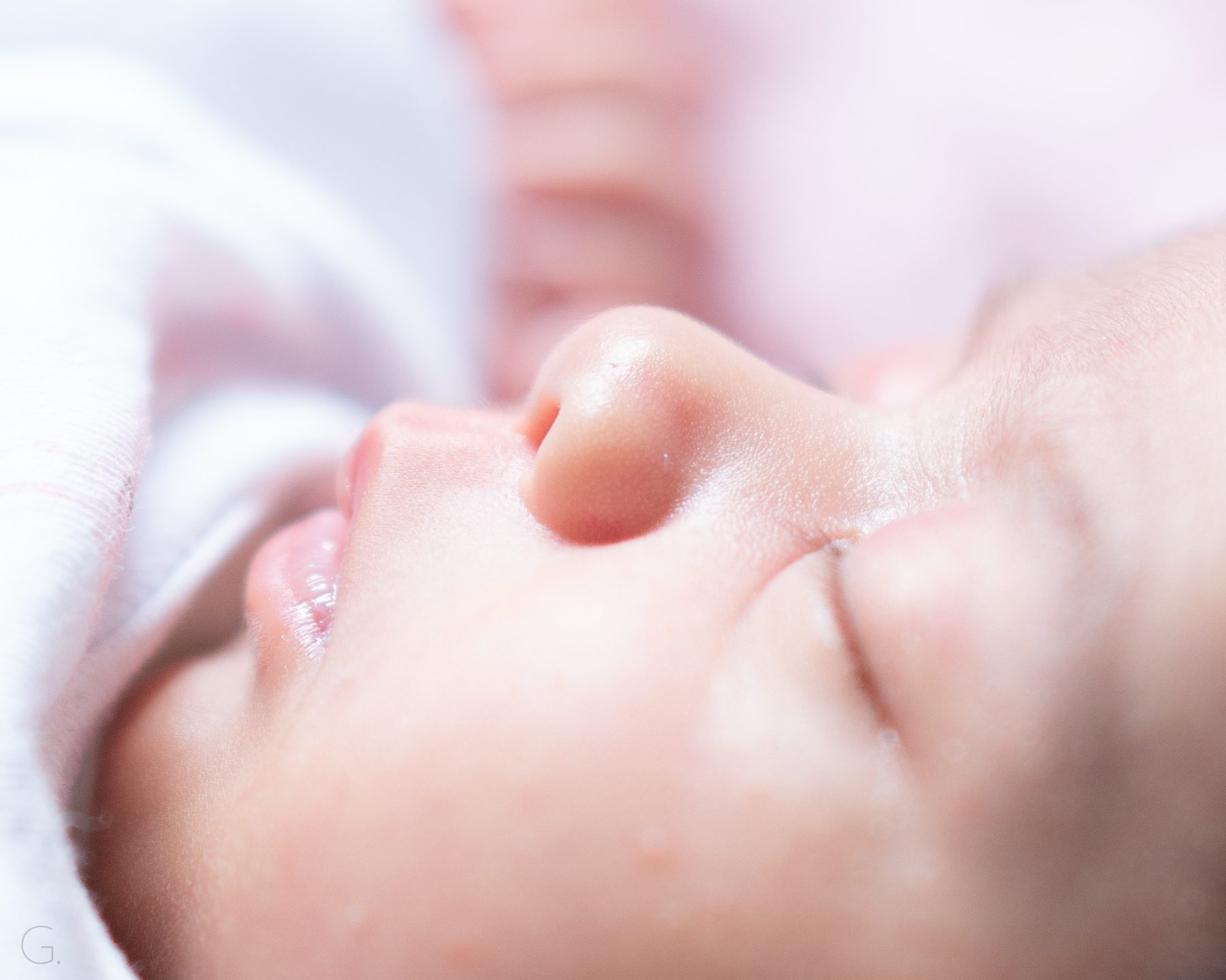 Macro of a newborn's nose and lips in soft pink light