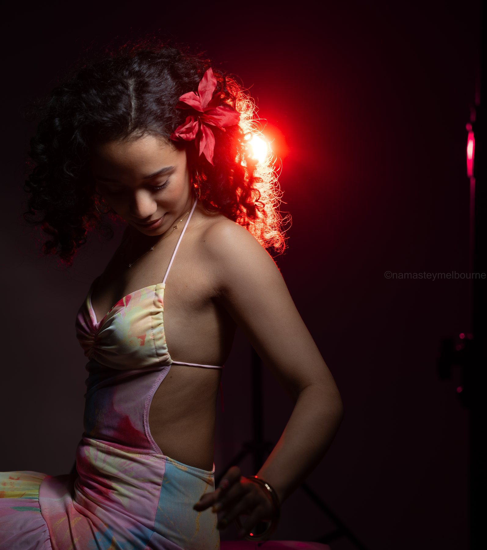 Studio portrait — red rim light through curly hair, flower behind the ear, Melbourne studio
