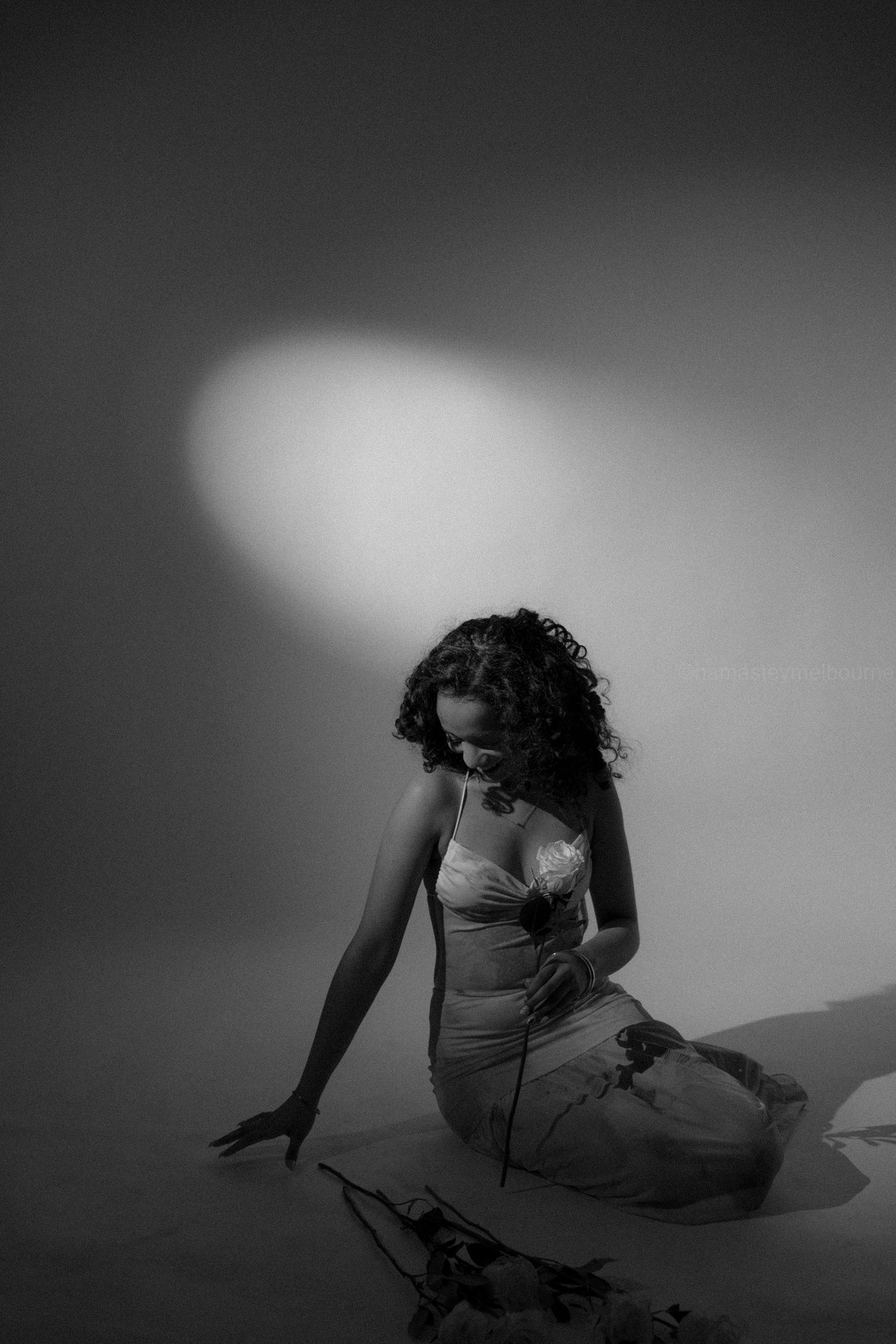 Black and white studio portrait — spotlight on the backdrop, rose in hand, Melbourne studio